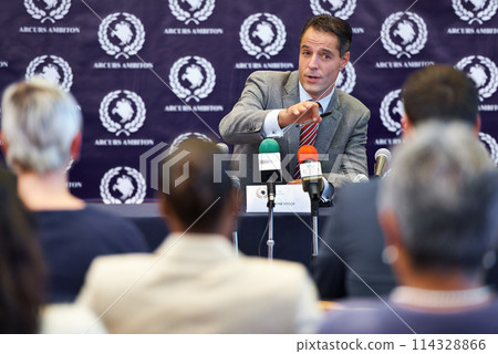 Politician man, press conference and announcement on news with journalist group in audience for questions. People, interview and story with information for public relations, global seminar and crowd Politician man, press conference and announcement on news with journalist group in audience for questions. People, interview and story with information for public relations, global seminar and crowd 114328866
