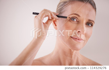 Cosmetics, portrait and woman with eyeliner in studio for beauty, natural and self care routine. Makeup, senior and female person with cosmetology product for facial treatment by white background. Cosmetics, portrait and woman with eyeliner in studio for beauty, natural and self care routine. Makeup, senior and female person with cosmetology product for facial treatment by white background. 114329276