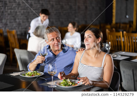 Senior man spending time with young girl in restaurant 114329279