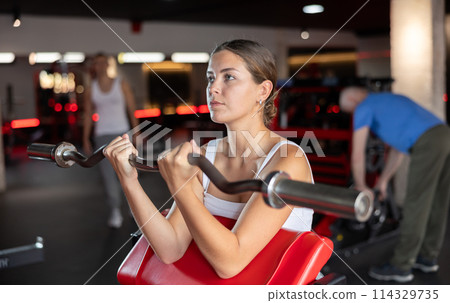 Young woman training with barbell in gym Young woman training with barbell in gym 114329735