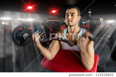 Sporty man performing set of exercises with barbell during intense workout Sporty man performing set of exercises with barbell during intense workout 114329820