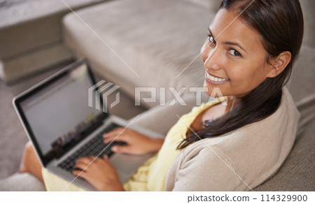 Woman, laptop and work from home on sofa with research, copywriting and planning online. Portrait of a young person, freelancer or writer typing on her computer, website or blog and relax on a couch 114329900