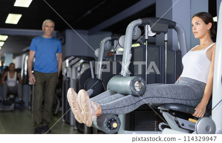 Young woman training her legs on machine Young woman training her legs on machine 114329947