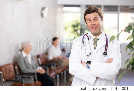 Adult male doctor posing in clinic reception Adult male doctor posing in clinic reception 114330013