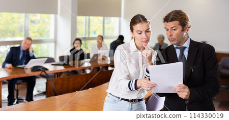 Middle aged white male manager discussing report with a young white subordinate female worker Middle aged white male manager discussing report with a young white subordinate female worker 114330019