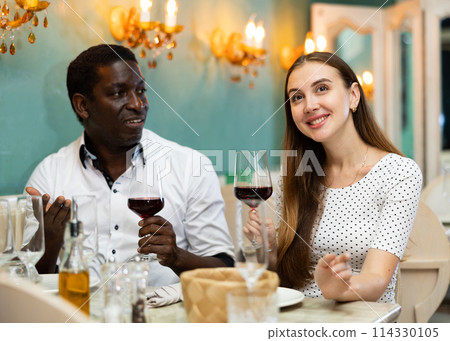 Loving positive smiling pair enjoying evening meal and conversation at cozy restaurant 114330105