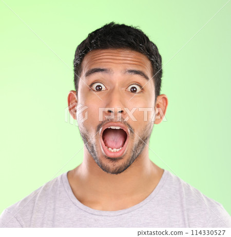 Excited, shock and portrait of man in studio with amazing news, happy announcement and mouth open. Surprise, omg and male person with emoji face for gossip, drama and wow emotion on green background. 114330527