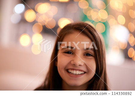 Home, happy and portrait of child with in bedroom for relaxing, resting and calm at night. Youth, smile and face of young girl with fairy lights for childhood memories, positive and happiness 114330892