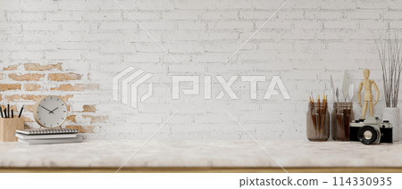 A white marble tabletop features painting tools and a space against the white brick wall. 114330935