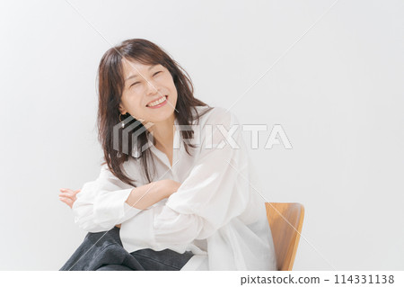 A middle-aged woman wearing a white shirt and smiling 114331138