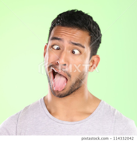 Man, crosses eyes and tongue in studio, silly and goofy comic or funny face on green background. Male person, mockup space and emoji for joke or comedy humor, student and quirky or crazy character 114332042