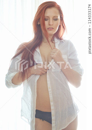 Woman, calm and sexy or seductive with shirt for temptation, flirty and sensual in bedroom with confidence. Girl, unbutton and serious in home for desire or sensuality, alluring and hot with cleavage Woman, calm and sexy or seductive with shirt for temptation, flirty and sensual in bedroom with confidence. Girl, unbutton and serious in home for desire or sensuality, alluring and hot with cleavage 114333174