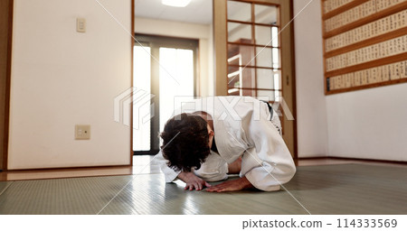 Aikido student, man or bow in dojo for training practice, discipline and black belt in class. Respect, greeting and Japanese person on floor with traditional gesture, culture and martial arts in gym. 114333569