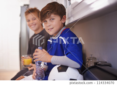 Children, portrait and soccer ball as friends in home with drink for sports training in kitchen for exercise, workout or juice. Male people, athlete and face in apartment with water, cardio or kit 114334070