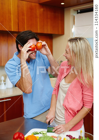 Happy, man and woman in cooking, smile and playful in kitchen at home for dinner, plans and family. Married couple in preparing, food or salad for healthy, eating and nutrition in house with tomatoes 114334160