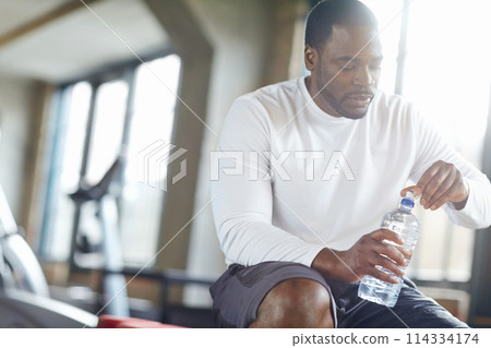 Gym, fitness and black man with water for training recovery, break or body hydration after exercise. Sports, liquid and African athlete with mineral drink for health, wellness and workout balance Gym, fitness and black man with water for training recovery, break or body hydration after exercise. Sports, liquid and African athlete with mineral drink for health, wellness and workout balance 114334174