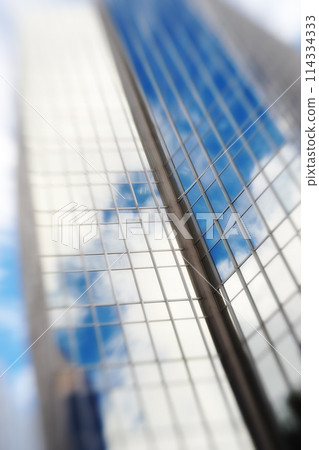 Blurry, building and window of skyscraper in city with reflection of blue sky and clouds on glass. Urban, office and architecture of tower or hotel with trippy motion for vertigo from heights in town Blurry, building and window of skyscraper in city with reflection of blue sky and clouds on glass. Urban, office and architecture of tower or hotel with trippy motion for vertigo from heights in town 114334333