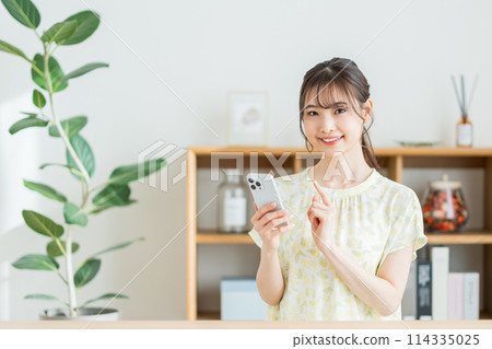 A woman who operates a smartphone in the living room. 114335025