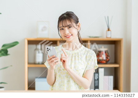 一個在客廳裡操作智能手機的女人。 一個在客廳裡操作智能手機的女人。 114335027