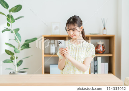 A woman who operates a smartphone in the living room. 114335032