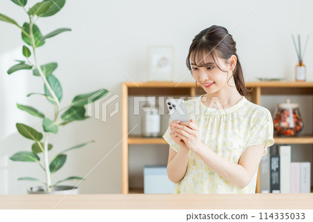 一個在客廳裡操作智能手機的女人。 一個在客廳裡操作智能手機的女人。 114335033