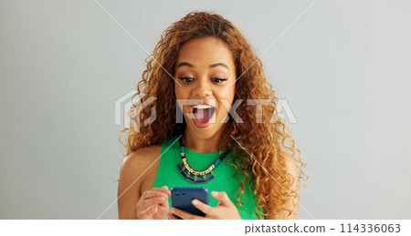 Excited woman, winner and phone with good news for lottery, prize or promotion on a gray studio background. Happy female person dancing with smile and mobile smartphone for celebration or success 114336063