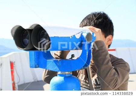 一個男孩不帶安裝在旅遊設施的大型雙筒望遠鏡 一個男孩不帶安裝在旅遊設施的大型雙筒望遠鏡 114338029