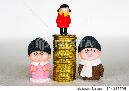 Between mother and father toy figures pile of coins with a child on it, concept of inheritance Between mother and father toy figures pile of coins with a child on it, concept of inheritance 114338796