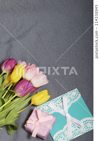 Bouquet of tulips of different colors on a gray background. Next greeting card and gift wrapped. Bouquet of tulips of different colors on a gray background. Next greeting card and gift wrapped. 114338945