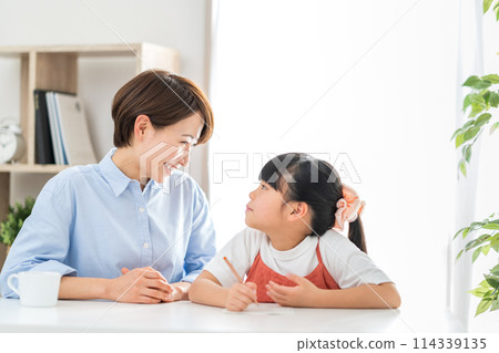 一名小學生和她的媽媽在客廳做作業。 一名小學生和她的媽媽在客廳做作業。 114339135
