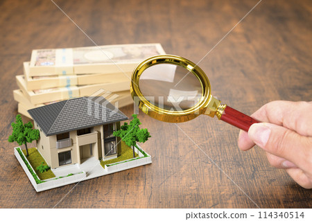 A miniature house and a stack of bills (+magnifying glass) 114340514