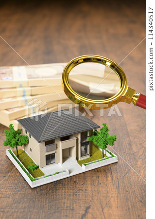A miniature house and a stack of bills (+magnifying glass) 114340517