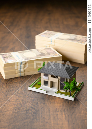 Miniature house and stack of bills 114340521