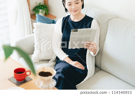 一個女人在客廳讀英文報紙 114340953