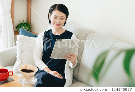 一個女人在客廳讀英文報紙 114340957