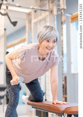 中年婦女在健身房進行肌肉訓練 114341183