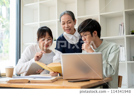 A mature Asian female professor helping her students in the classroom, explaining some hard topics. A mature Asian female professor helping her students in the classroom, explaining some hard topics. 114341948