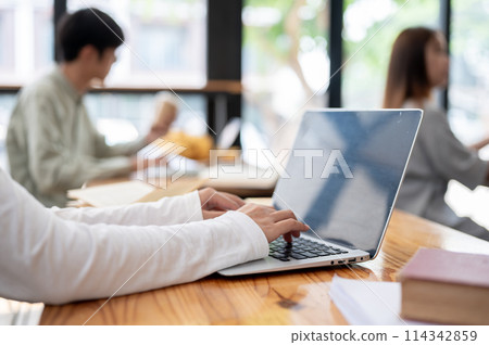 A close-up image of a college student using her laptop computer in the classroom. A close-up image of a college student using her laptop computer in the classroom. 114342859