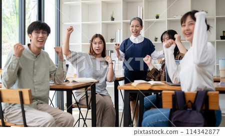 A cheerful mature Asian female teacher with her students showing their fist, celebrating good news. A cheerful mature Asian female teacher with her students showing their fist, celebrating good news. 114342877