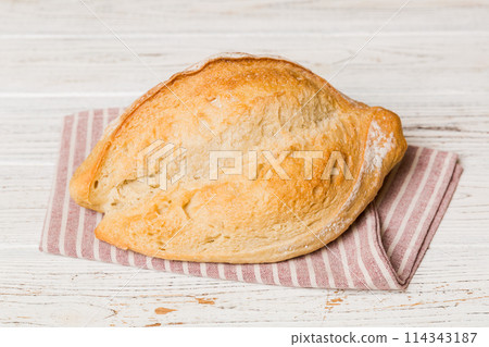 freshly baked bread with napkin on rustic table top view. Healthy white bread loaf isolated 114343187