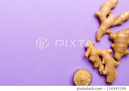 Finely dry Ginger powder in bowl with green leaves isolated on colored background. top view flat lay Finely dry Ginger powder in bowl with green leaves isolated on colored background. top view flat lay 114343199