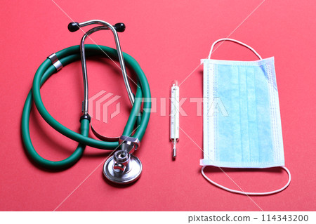 Top view of stethoscope, medical protective mask and thermometer on colorful background. Medical accessories concept Top view of stethoscope, medical protective mask and thermometer on colorful background. Medical accessories concept 114343200