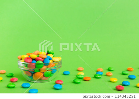 Multicolored candies in a bowl on a colored background. birthday and holiday concept. Top view with copy space 114343251