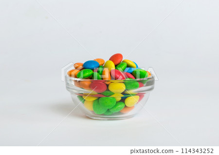 Multicolored candies in a bowl on a colored background. birthday and holiday concept. Top view with copy space 114343252
