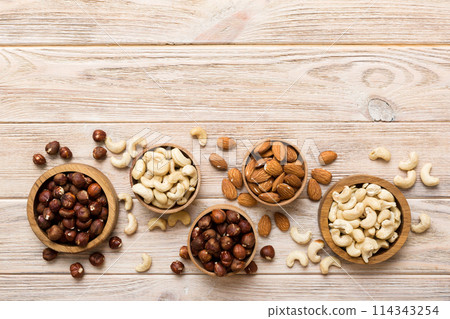 Assortment of nuts in wooden bowl on colored table. Cashew, hazelnuts, walnuts, almonds. Mix of nuts Top view with copy space Assortment of nuts in wooden bowl on colored table. Cashew, hazelnuts, walnuts, almonds. Mix of nuts Top view with copy space 114343254