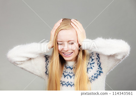 Happy blonde woman holding head out of joy Happy blonde woman holding head out of joy 114343561