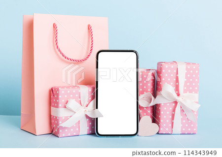 mobile phone with blank screen on colored background with hearts, calendar and gift box, valentine day concept perspertive view flat lay mobile phone with blank screen on colored background with hearts, calendar and gift box, valentine day concept perspertive view flat lay 114343949
