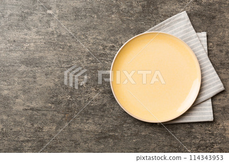 Top view on colored background empty round yellow plate on tablecloth for food. Empty dish on napkin with space for your design 114343953