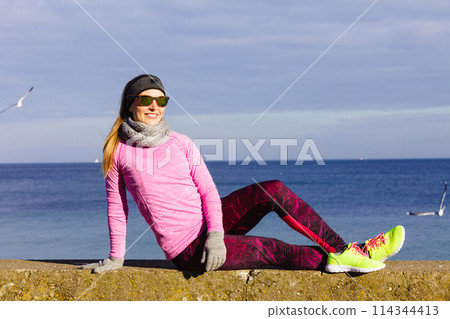 Woman resting after doing sports outdoors on cold day Woman resting after doing sports outdoors on cold day 114344413