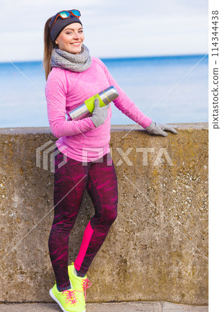 Fit woman in cold day warming up drink tea 114344438